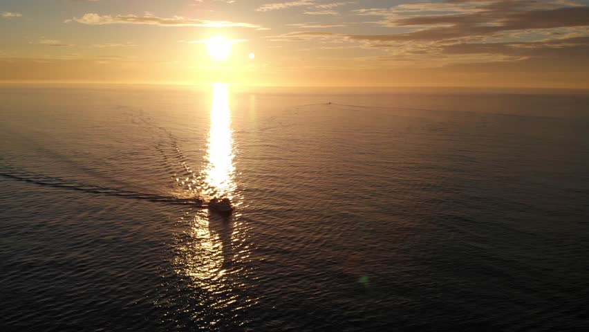 Torrevieja fishing boat and the rising sun at the harbor entrance seen from the air with a drone in the morning.