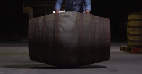 Large whiskey sherry barrel keg rolling toward camera slow motion
