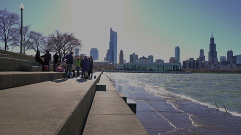 Chicago, IL / USA - April 20, 2017: People gather for a picnic along Lake Michigan, with the city skyline in the distance, on a cool spring day.