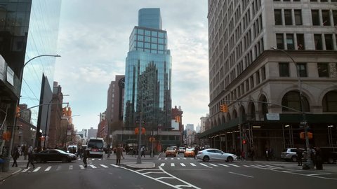 NEW YORK - APR 17, 2019: glass building in Cooper Square cars and taxis driving on street Manhattan New York City NYC. Cooper Square separates East Village from Greenwich Village.