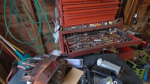 Tools and various parts and equipment in a large tool box and strewn on a work table in an old garage
