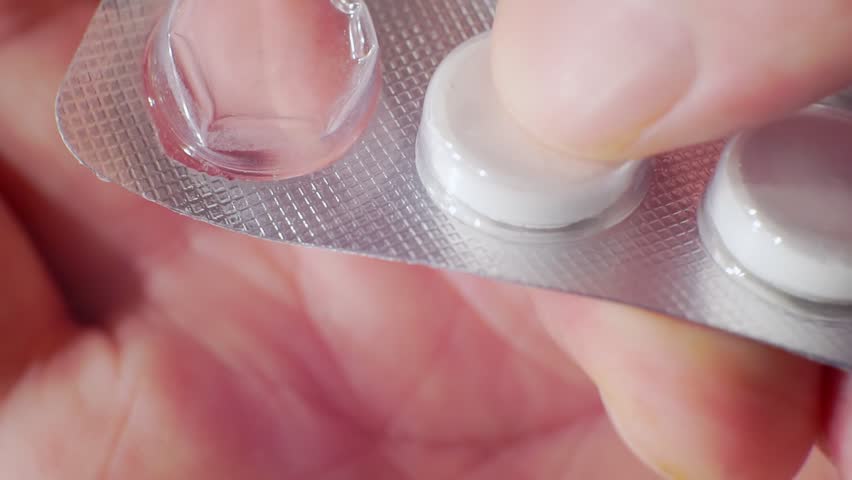 Fingers take out the white pills from the blister pack.close-up.shallow depth of field. | Shutterstock HD Video #1028047325