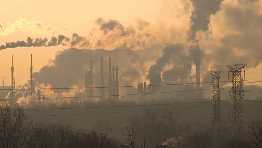 Smokestacks from an oil refinery in the morning sunlight spewing out hazardous polluting fumes causing global warming Royalty-Free Stock Footage #1028048900