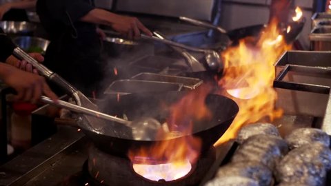 Slow motion view of frying pans with vegetables and wok on big fire at street cafe in Siem Reap, Cambodia
