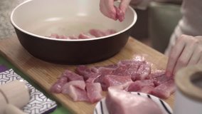 The girl puts the cut on the Board meat pork beef in a frying pan with oil, close-up, cooking, fast video, time lapse