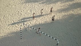 Soccer players in dynamic action funny play on the sand in beach football in summer sunny day under sunlight. Aerial View, Drone 4K Video.