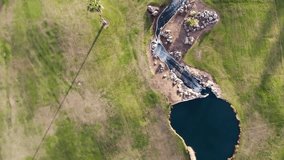 Aerial view of golf course. Cinematic top view 4K footage with green grass, ponds, watercourses, palm trees, patches, holes, flags. Evening time shot during sunset, soft golden light 