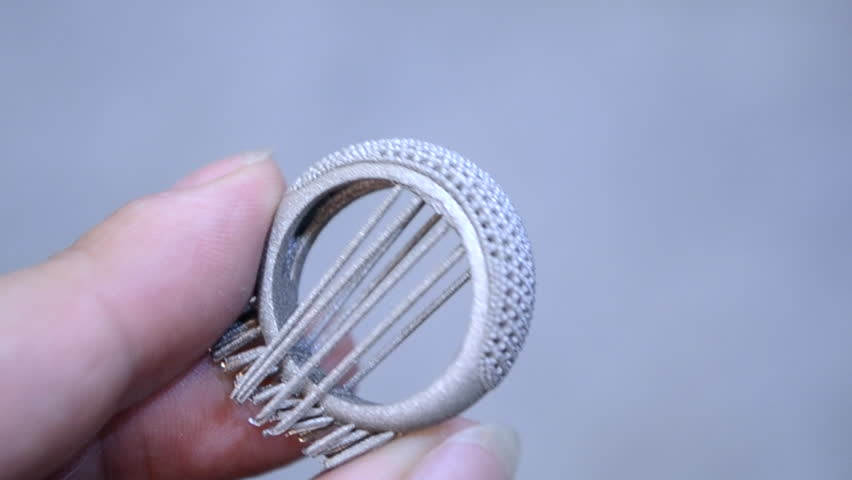 Man is holding object printed on metal 3d printer. Object printed in laser sintering machine. Modern 3D printer printing from metal powder. Progressive additive DMLS, SLM, SLS 3d printing technology