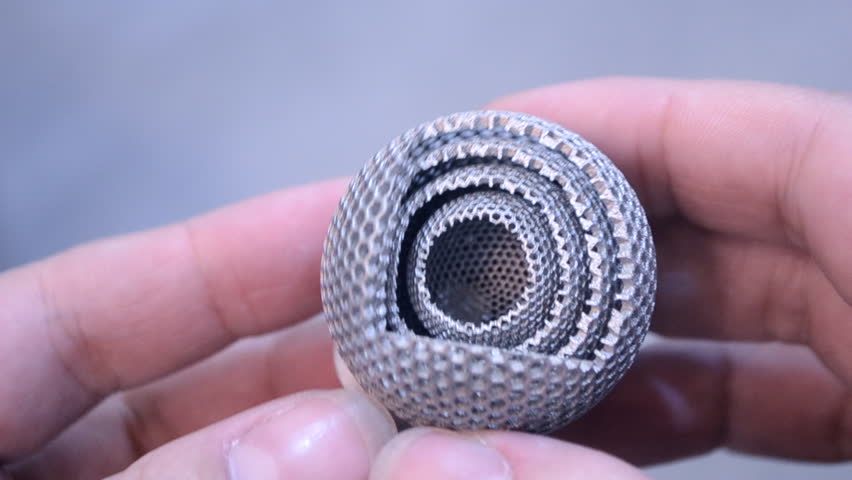 Man is holding object printed on metal 3d printer. Object printed in laser sintering machine. Modern 3D printer printing from metal powder. Progressive additive DMLS, SLM, SLS 3d printing technology