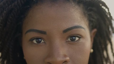 Closeup shot of smiling African American woman looking at camera. Young woman with brown eyes. Face features concept