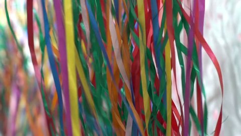 Colored wackies or streamers, long confetti or paper string decorations waving from the bottom to the top during an outdoor party. Slow motion.