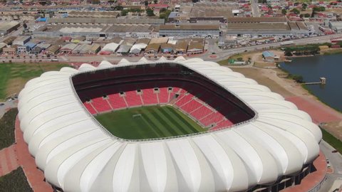 Port Elizabeth, South Africa - circa 2010s: Aerial orbit of Nelson Mandela Bay Stadium. Close view of stadium, see seats and soccer field with industrial area and North End Lake in background
