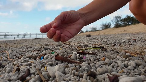A person picking up plastic washed on a popular beach close to a city. Filmed at 60 fps