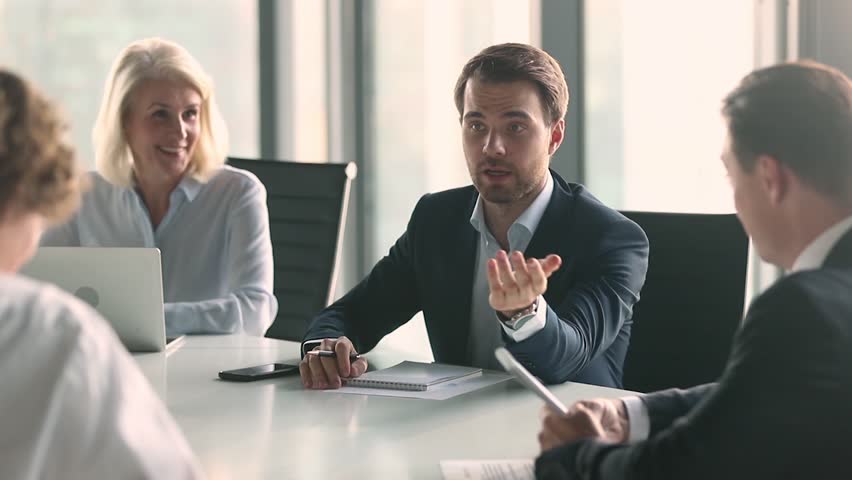 Businessman in suit talking to business people colleagues or partners sitting at conference table, male leader discussing work at team meeting or group negotiations having conversation with clients Royalty-Free Stock Footage #1028099081