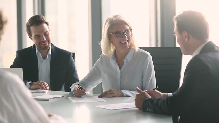 Old businesswoman and middle aged businessman partners negotiate sign contract handshake at group meeting sit at table, senior female client and male manager make agreement shake hands at negotiation | Shutterstock HD Video #1028099087