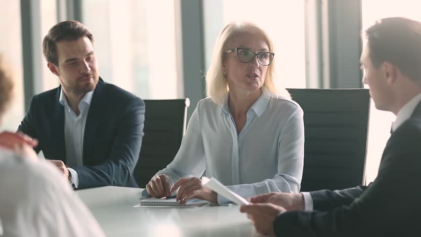 Mature old female company leader negotiator handshake male business partner or client make work deal formal agreement shake hands sitting at negotiation table express gratitude at team office meeting | Shutterstock HD Video #1028099093