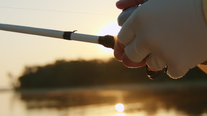 Fisherman Reels in Fish During Sunset - Closeup