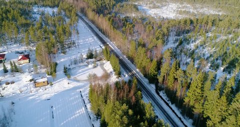 Aerial, drone shot, panning around a car turning on a forest road, driving on a slushy countryside route, between, green trees, on a sunny, spring day, in Tejio national park, Finland