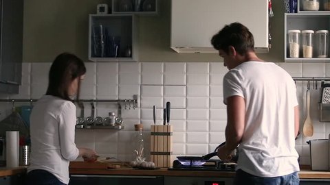 Funny couple rear view dancing while cooking together in kitchen, young active family having fun laughing feels carefree happy enjoy preparation food breakfast or dinner lifestyle leisure mood concept