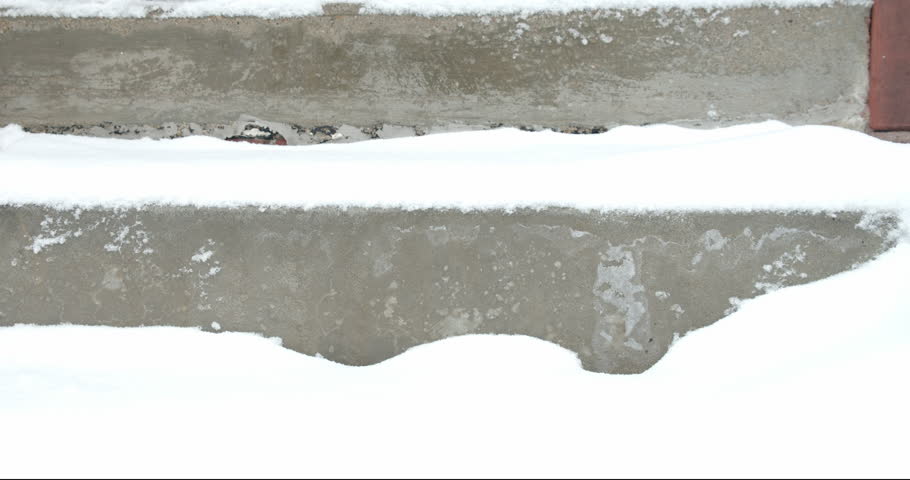 Person wearing boots walks down steps with fresh snow