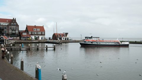 Blue orange boat sailing on the sea in Volendam with some passengers on boart. Boat enters port Volendam Netherlands 3.18.2019