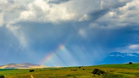 The rainbow glows in the sunlight against the background of dark clouds. Shadows of the sun move along the wheat fields. 4K TimeLaps - Powered by Shutterstock - Get 15% off with code: PIKWIZARD15