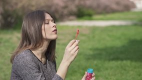 Beautiful Young Woman Making Soap Bubbles and Having Fun in the Park, Slow Motion Clip