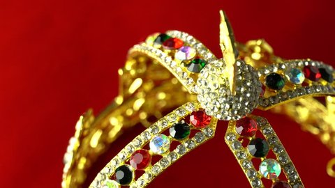 Diamond gold crown for royal person ceremony. Diamond crystal tiara frame jewellery decoration gems stones and red velvet background, slow motion rotation spin macro close up to the middle frame. 4k.
