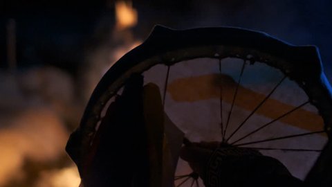 The silhouette of a shaman's tambourine near the fire.