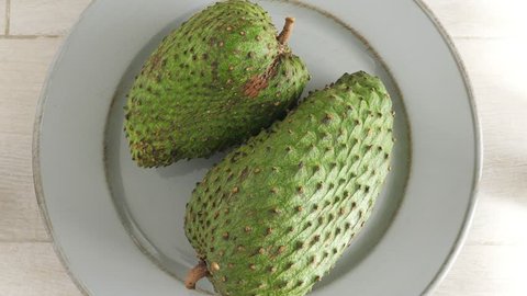 Closeup of green soursop graviola, exotic, tropical fruit Guanabana on plate, Rotate