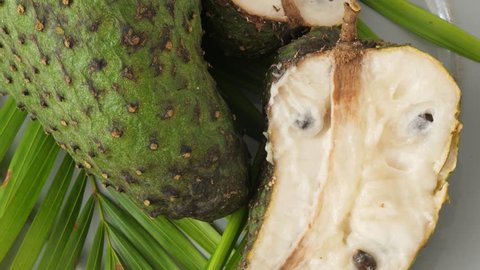 Closeup of green soursop graviola, exotic, tropical fruit Guanabana on plate, Rotate