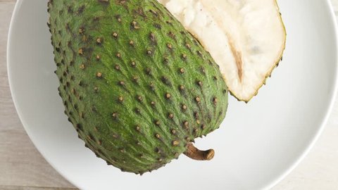Green soursop graviola, exotic, tropical fruit Guanabana on plate, Rotate