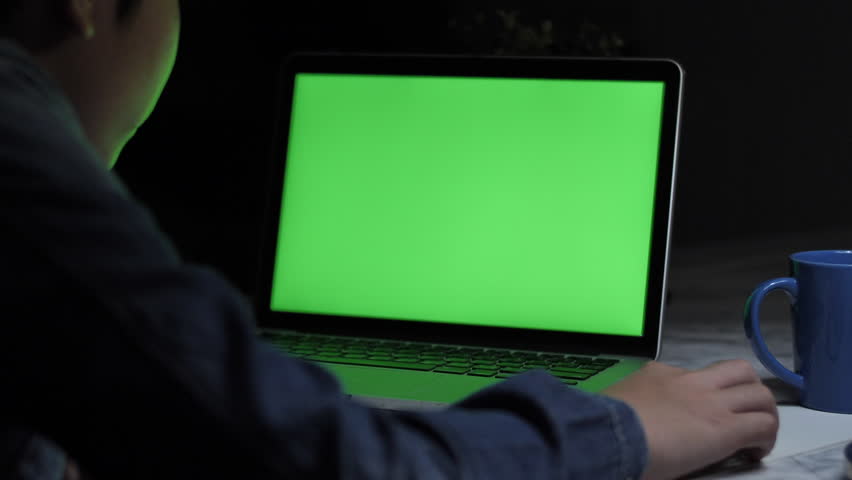 Over the shoulder shot of a young boy using on laptop computer on desk, looking at green screen. Dolly shoot 60fps. Royalty-Free Stock Footage #1028127611
