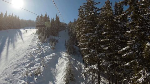 Ride on a ski lift next to a ski track that goes between trees