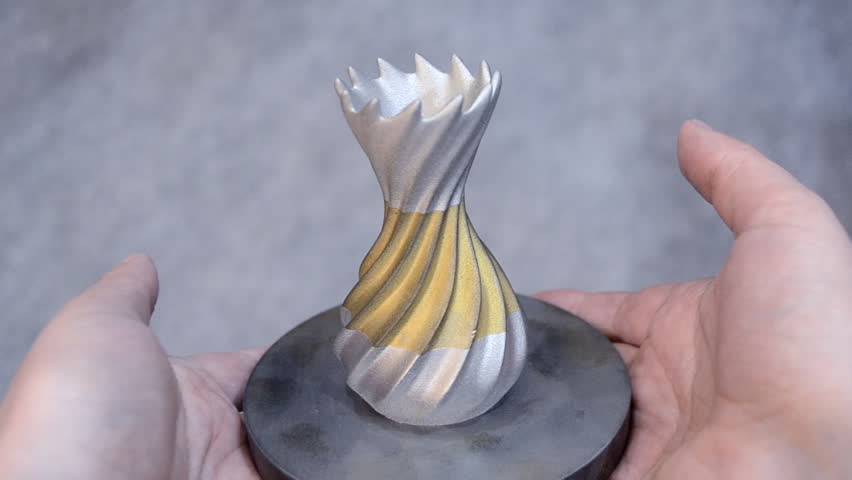 Man is holding object printed on metal 3d printer. Object printed in laser sintering machine. Modern 3D printer printing from metal powder. Progressive additive DMLS, SLM, SLS 3d printing technology