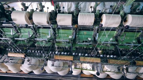 Textile factory equipment spools threads onto bobbins.