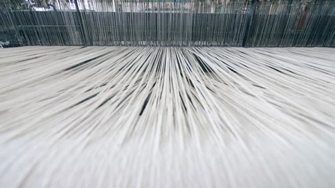 A loom weaving threads, working automatically at a factory.