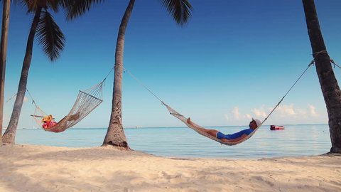Man and woman relaxing in a hammock on tropical island beach
