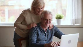 Old couple spend time at home husband sitting at table wife stands behind him family plan vacation use internet resource apps, search eyesight correction clinic, medical insurance better offer concept - Powered by Shutterstock - Get 15% off with code: PIKWIZARD15