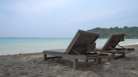 A pair of wooden sun loungers on a sandy beach overlooking the sea. - Powered by Shutterstock - Get 15% off with code: PIKWIZARD15