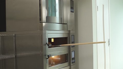 A demonstration video of a baker taking out freshly baked bread from the oven. Baking bread in the bakery shop. Crispy fresh bread