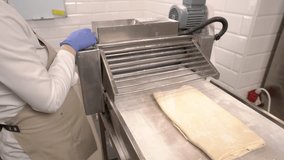 Commercial Bakery. Dough being put through a rolling machine. Close-up demonstration video