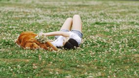 Slow motion, Chinese girl and golden retriever lie together outdoor on a grass covered with flowers enjoy leisure time. Chinese girl holding flowers and dog play and lie on the soft grass happily. - Powered by Shutterstock - Get 15% off with code: PIKWIZARD15