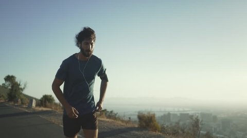 Morning jogger moves hands running up valley hill