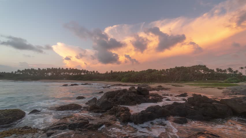 Sunset at Sri Lanka beach in the south coast at Tangalle Hiriketiya. Clouds rush by and turn orange during beautiful golden hour looking over the ocean.  4K time-lapse
