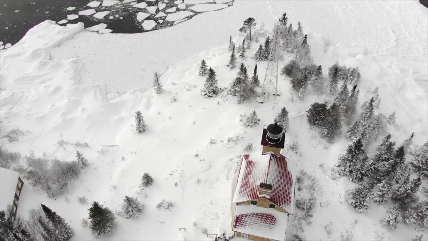 Lighthouse in Northern Michigan over looking Lake Superior Ice Floating near Snow Covered Beaches.