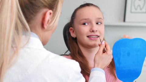 Female orthodontist examining child's teeth in dentist's office