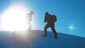 teamwork tourists winter snow business travel trip lends a helping hand. two men with backpacks hiking help each other silhouette in lifestyle mountains with sunlight. slow motion video. rock climbers