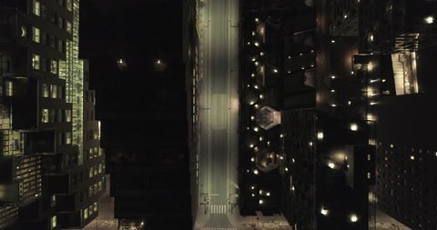 4K aerial video with forward motion and a birds eye view of the dark rooftops of financial- and apartment buildings and an illuminated empty street at night in downtown Oslo, Norway.