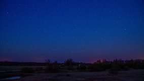 Time lapse of the night sky with moon rising and illuminating the landscape